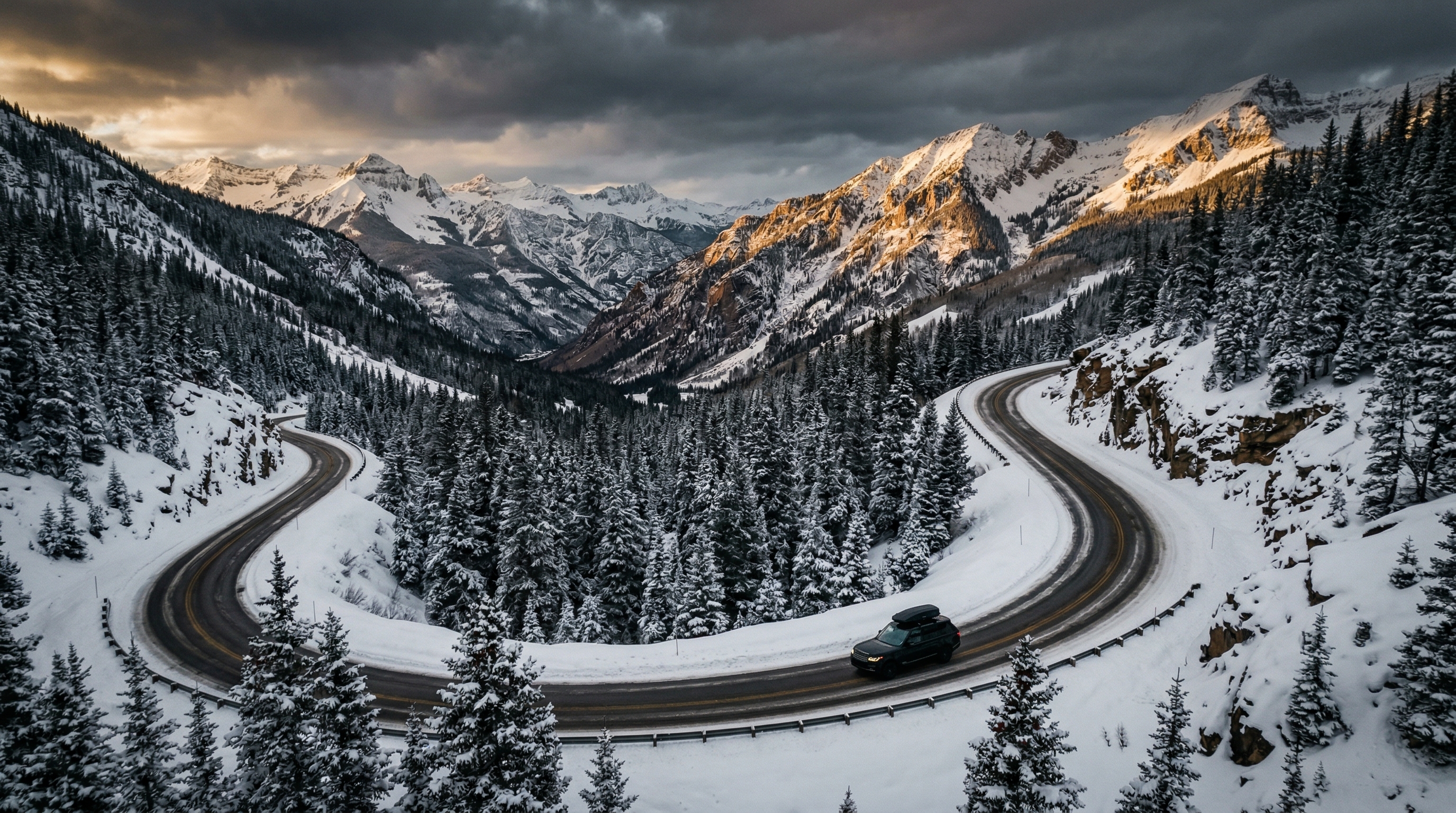Black SUV driving on a snowy mountain highway through the San Juan Mountains